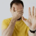 hombre tapándose la cara con la mano