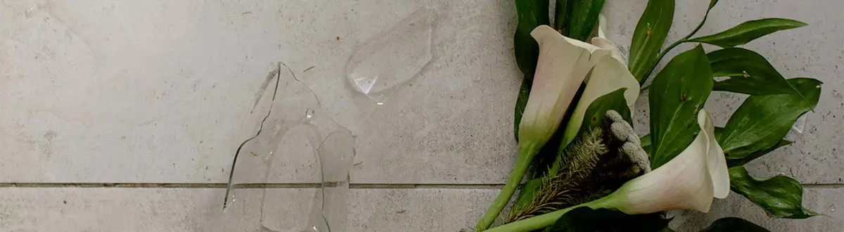 jarron de cristal con flores roto en el suelo